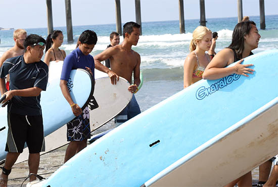 Students holding surfboards at the beach near Scripps Pier, recreation class, UC San Diego